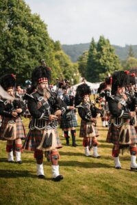 pexels-photo-31467530-31467530 Men in traditional Scottish attire playing bagpipes outdoors during day parade in Scotland.